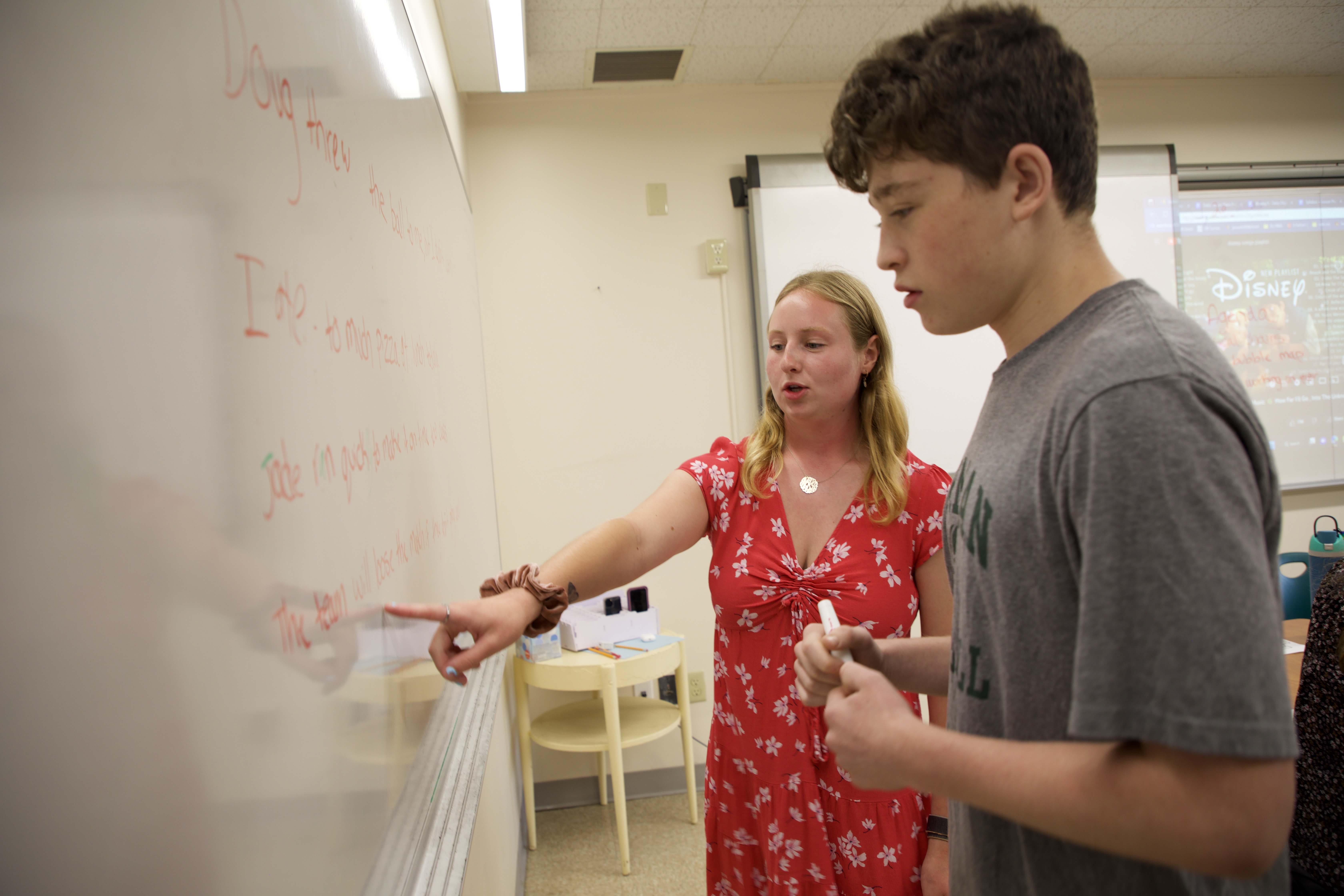 Woman and boy read text on whiteboard in classroom